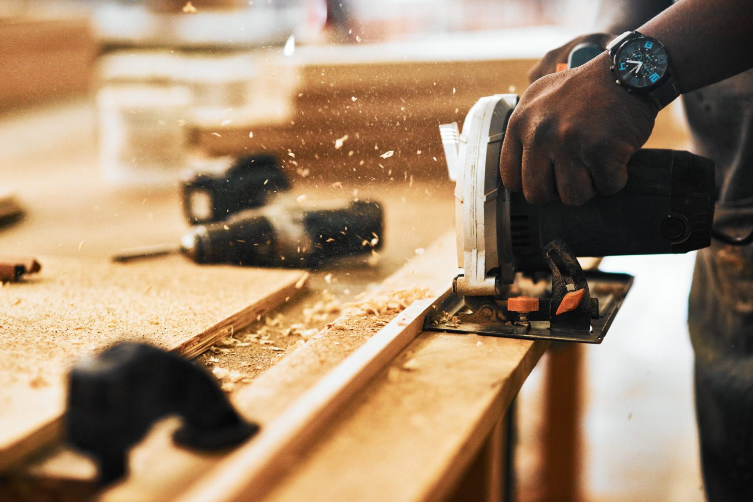 Cropped shot of an unrecognizable carpenter using a circular saw to cut wood inside a workshop.